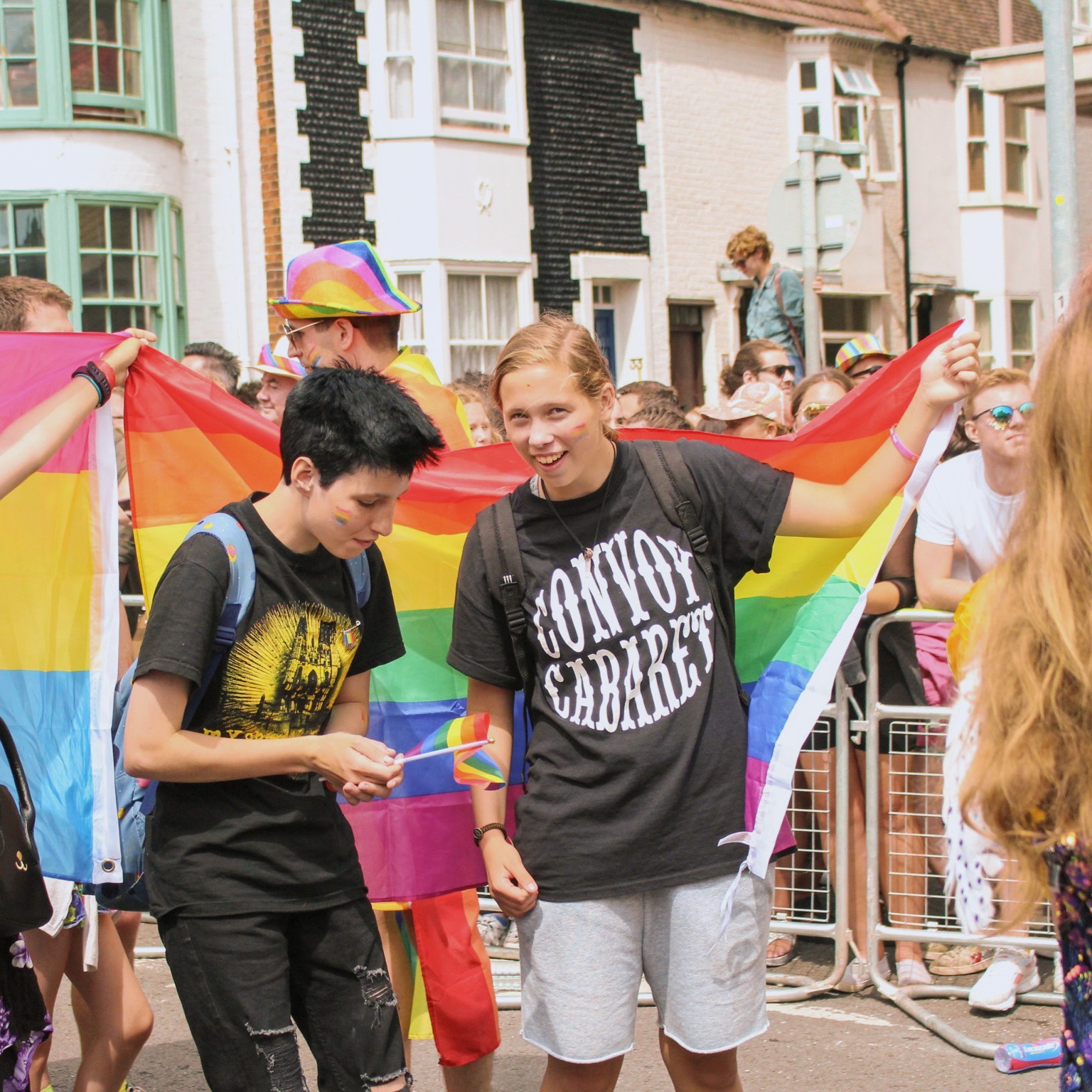 Photo of some walkers in Brighton Pride (2019) holding a pride flag between two teenagers